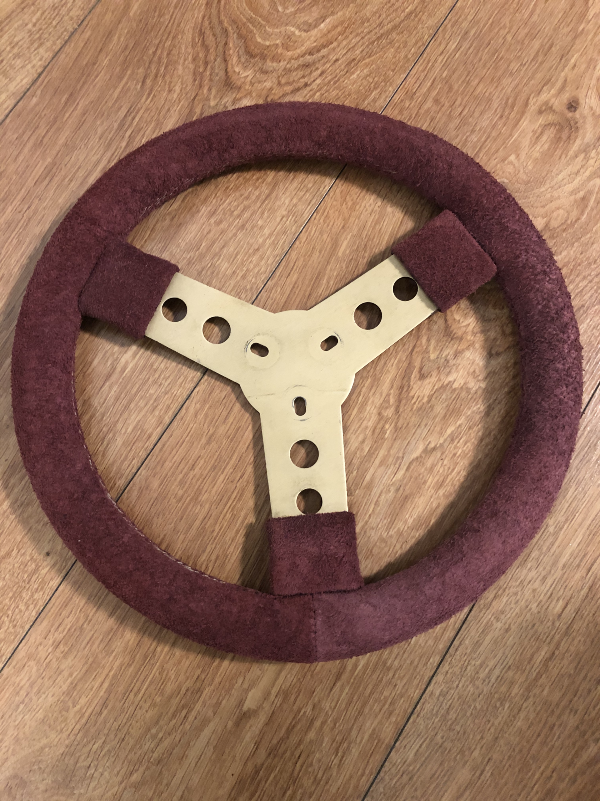 Restored three-spoke motorsport steering wheel with burgundy suede-style rim